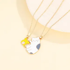 Detailed view of gold couple necklaces featuring a cute enamel cat and hamster pendant