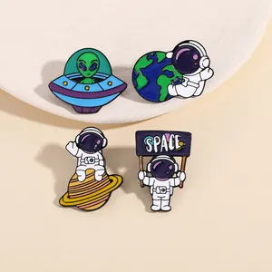 Set of four space-themed enamel pins featuring astronauts and aliens on a flat surface
