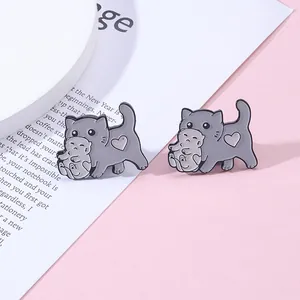 Détail de broches en émail représentant un chat gris portant son chaton dans sa gueule