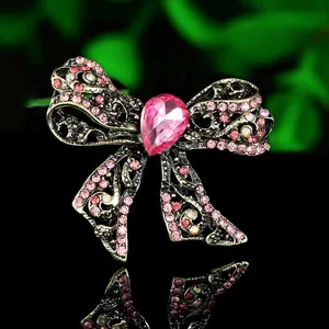 Macro shot of luxury pink rhinestone bow brooch with intricate gold-toned hollow carvings