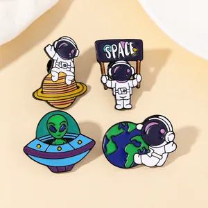 Detail of space enamel pin set featuring astronauts, green aliens and UFO on beige background