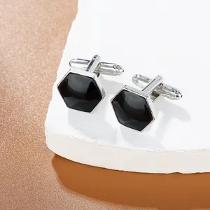 Polished silver hexagonal cufflinks with black enamel inlay on white pedestal