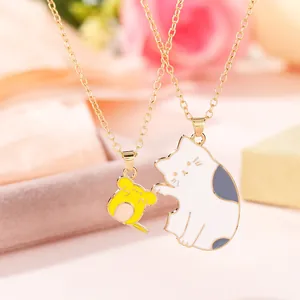 Close-up of golden couple necklaces with cartoon oil-dripped cat and mouse pendants