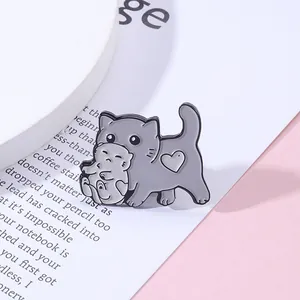Détail de la broche chat en émail gris avec motif cœur et chaton sur fond doux