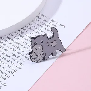 Détail d'un pin's en émail montrant un chat gris tenant un chaton avec un motif de cœur
