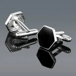 Detailed close-up of hexagonal silver and black cufflinks on a reflective surface