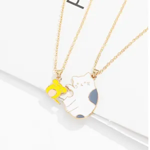 Close-up of cute cartoon hamster and cat enamel pendants on gold chains for couples