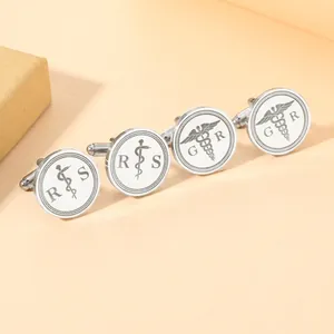 Detailansicht silberner Manschettenknöpfe mit Caduceus-Symbolen und eingravierten Initialen