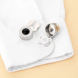 Polished silver button cover with black gemstone inlay on a white shirt cuff