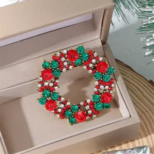 Close-up of a sparkling Christmas wreath brooch with red and green crystals in a gift box