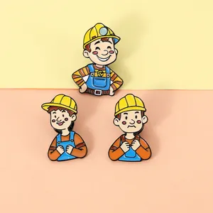Detailed view of three cartoon construction worker enamel pins with yellow hard hats