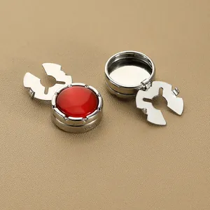 Primer plano de cubrebotón de metal plateado con incrustación roja en fondo de cuero