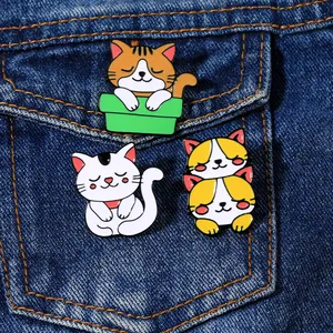 Dettaglio di spille in smalto con gatti su tasca in denim con gattini bianchi e arancioni
