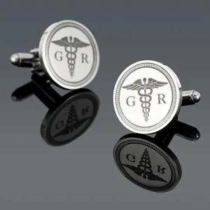 Makroaufnahme silberner Manschettenknöpfe mit Caduceus-Symbol und G-R-Gravur