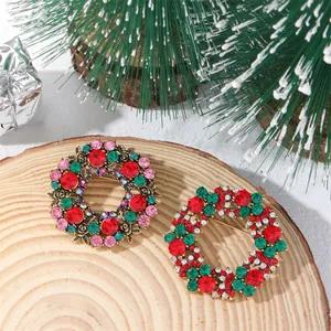 Detail of Christmas wreath brooches with colorful rhinestones on a rustic wood slice