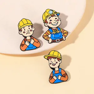 Three cartoon construction worker enamel pins on a beige tray, cute creative metal badges