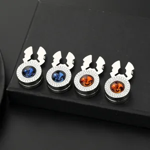 Macro detail of four luxury magnetic brooches with blue and amber crystals on black background