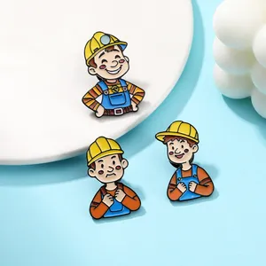 Detailed close-up of three cute cartoon builder enamel pins on a blue and white display