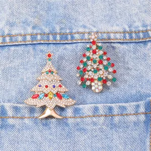 Macro shot of two festive crystal Christmas tree brooches on blue denim pocket texture