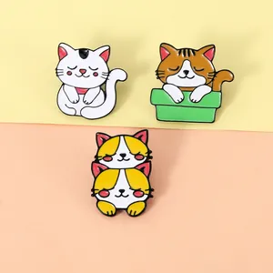 Dettaglio di tre simpatiche spille per gatti in smalto dai colori vivaci e bordi metallici