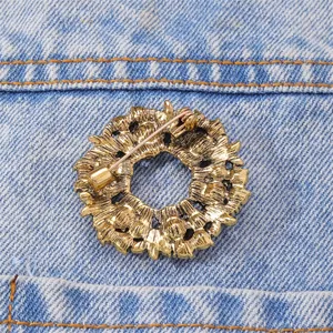 Detailed back view of a gold Christmas wreath brooch with secure safety pin clasp
