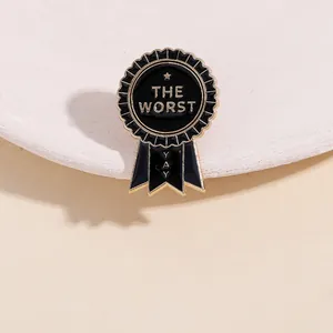 Close-up of a black enamel medal pin featuring golden The Worst and Yay text