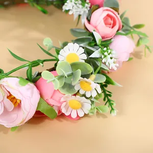 Nahaufnahme von rosa Stoffrosen und weißen Gänseblümchen auf einem Braut-Haarreif