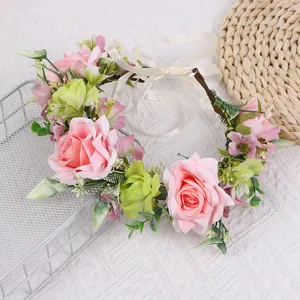 Detail von rosa Kunstrosen und grünen Blättern am Blumenkranz mit weißem Satinband