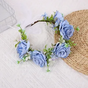 Detail of blue fabric rose crown with faux greenery and long white ribbon tie