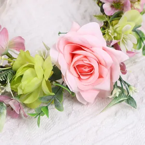Nahaufnahme realistischer rosa Samtrosen und grüner Blätter am Brautblumenkranz