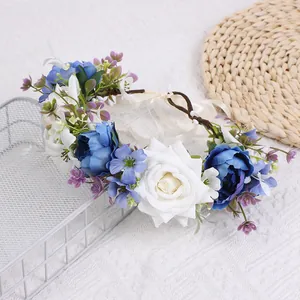 Detail eines Blumenkranzes mit blauen Rosen, weißen Seidenblumen und weißem Satinband