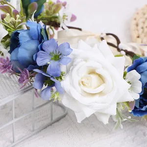 Nahaufnahme des handgefertigten Blumenkranzes mit weißen Rosen und blauen Blüten