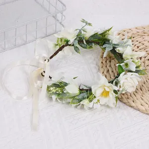 Détail de couronne florale de mariée avec roses blanches, feuilles vertes et ruban ivoire