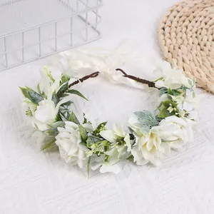 Détail de roses et lys en soie blanche sur un bandeau floral avec rubans beiges