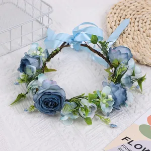 Détail d'une couronne de roses bleues avec feuilles vertes et ruban en soie