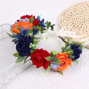 Detail eines Blumenkranzes mit roten und orangen Rosen, grünen Blättern und weißen Bändern