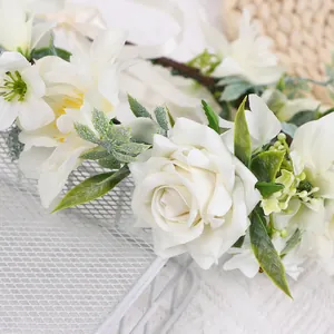 Vue détaillée des roses et lys blancs réalistes sur un bandeau floral fait à la main