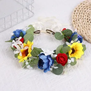 Détail d'une couronne de fleurs avec tournesol, rose rouge, pivoine bleue et ruban blanc