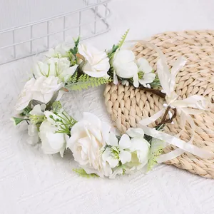 Détail d'une couronne de mariée blanche avec roses en soie et ruban sur tapis de paille