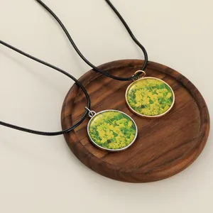Close-up of yellow flower necklaces in silver and gold frames on a wooden tray
