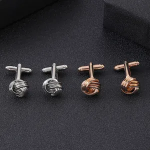 Détails macro de boutons de manchette torsadés en argent et or rose sur tapis noir
