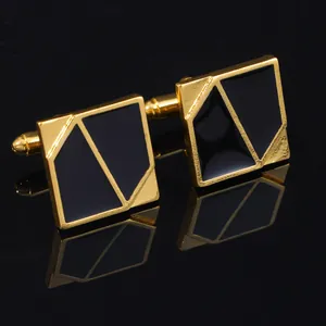 Detailed view of geometric gold and black cufflinks with elegant reflection on black surface