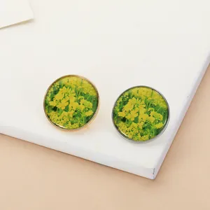 Close-up of gold and silver resin brooches with yellow rapeseed flower patterns