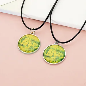Detail of round vintage pendant necklaces with vibrant rapeseed flower patterns and glass cover