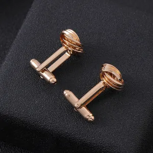 Gros plan de boutons de manchette tressés en or rose sur fond de texture noire