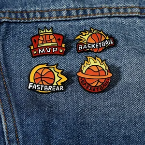 Dettaglio di quattro spille in smalto da basket su uno sfondo di jeans blu scuro