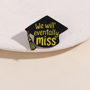 Detailed close-up of alloy enamel graduation pin with black cap and yellow tassels