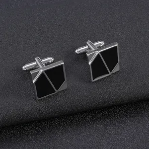 Detailed close-up of vintage silver cufflinks with black geometric enamel on black texture