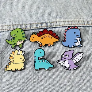 Set of 6 cute cartoon dinosaur enamel pins including T-Rex and Stegosaurus on denim