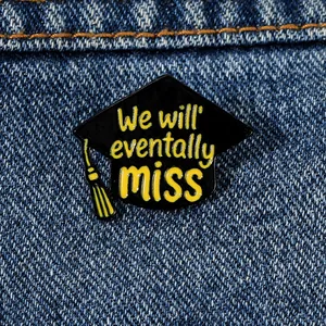 Close-up of a graduation cap enamel pin with yellow tassel on blue denim fabric